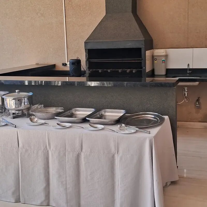 Área de churrasco com churrasqueira, mesa de bufê e estrutura de cozinha para confraternizações na Mimo Casa de Festa