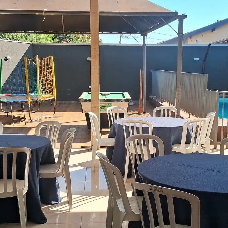 Vista geral da Mimo Casa de Festa com mesas redondas, área kids com cama elástica, mesa de sinuca e piscina ao fundo em Campo Grande MS